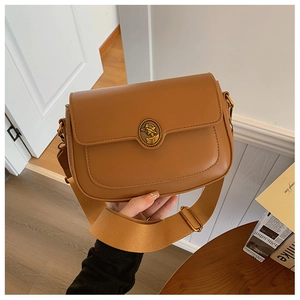 Detail of vintage brown crossbody bag with gold relief buckle and wide canvas strap