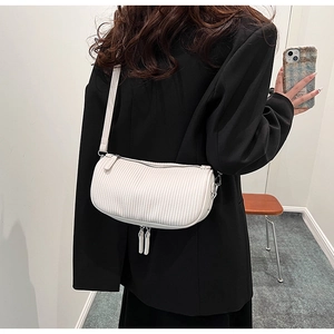Detail of white pleated cylindrical crossbody bag with long zipper pulls on shoulder