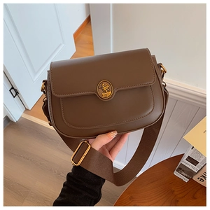 Detail of brown PU leather crossbody bag with vintage gold portrait ornament and wide strap