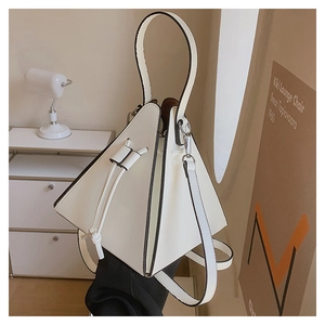 Détail du sac à main triangulaire en cuir blanc avec fermeture à cordon et bord noir