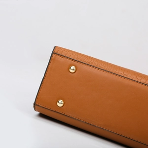 Side view of tan leather handbag with croc embossed texture and gold metal studs