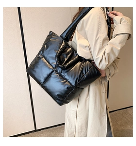 Fashionable black quilted down tote bag worn with a khaki trench coat in a cozy room
