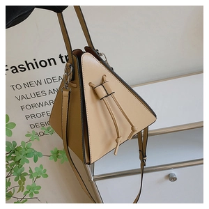 Vue détaillée du sac à main triangulaire en cuir beige avec cordon et détails argentés