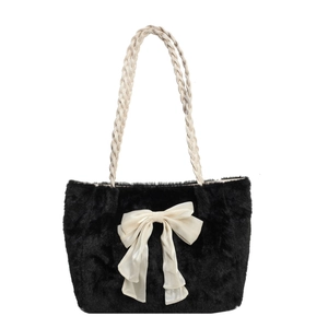 Black plush tote bag with white silk bow and braided rope handles on white background