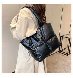 Detailed side view of black quilted puffer tote bag shown on a model's shoulder
