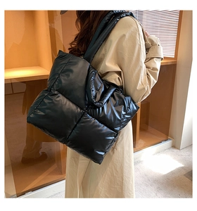 Detail view of large black quilted puffy tote bag with glossy finish and wide shoulder strap