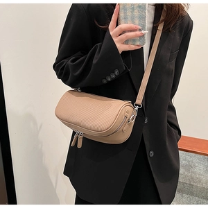 Macro detail of khaki cylindrical crossbody bag with textured leather and dual zippers