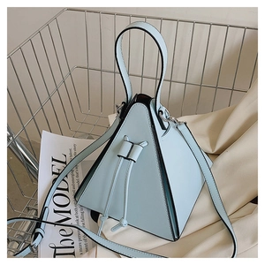 Détail macro du sac triangulaire en cuir bleu ciel avec accessoires en métal argenté