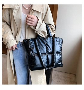 Close-up of black quilted puffer tote bag with glossy finish and dual strap design