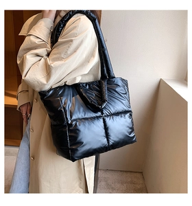 Detail of black quilted down tote bag in glossy nylon fabric shown on model
