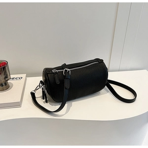 Macro view of black pleated cylinder bag with silver metal zipper and leather strap
