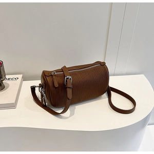 Macro detail of brown cylindrical crossbody bag featuring vertical striped texture and silver zip