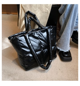 Detail of black quilted puffer tote bag with glossy finish and square lattice pattern
