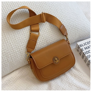 Detail of a brown vintage leather crossbody bag featuring a golden embossed metal buckle
