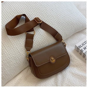 Close-up of brown vintage saddle bag featuring retro portrait relief metal buckle