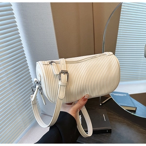 Detail of white pleated cylinder bag with zipper closure and metallic buckle strap
