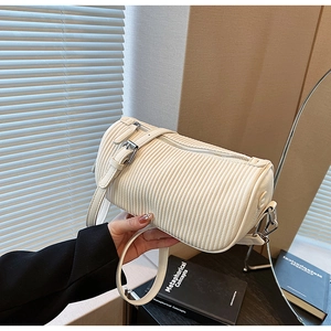 Detail of white pleated cylinder bag featuring silver metal hardware and leather strap