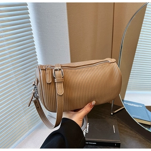 Detail of light khaki barrel bag with vertical pleated texture and silver zipper