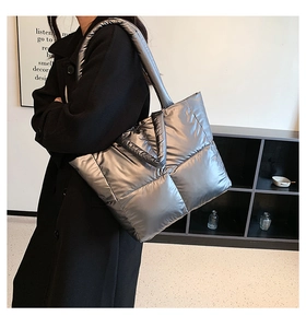 Detail view of large silver quilted down tote bag with wide shoulder strap and spacious design