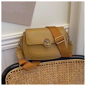 Detail of khaki saddle bag featuring vintage round metal logo and wide woven strap