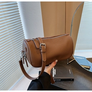 Detailed view of a brown leather cylinder bag with textured vertical stripes and silver zip