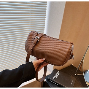 Detail of a brown cylindrical crossbody bag with pleated texture and metal hardware