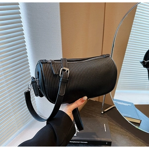 Detail of black pleated cylindrical pillow bag with silver zipper and leather strap