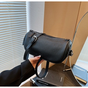 Close-up of black cylinder bag with vertical pleats and pebbled leather texture detail