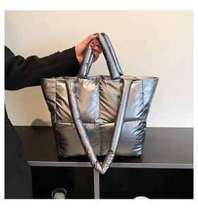 Macro detail of silver quilted tote bag made of high-gloss nylon with padded handles