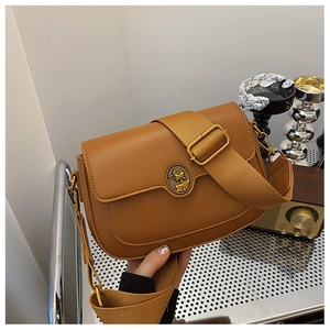 Close-up of vintage caramel faux leather bag with embossed gold emblem and canvas strap