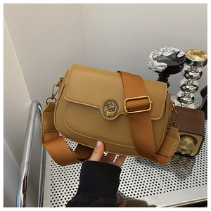 Detailed shot of retro brown crossbody bag with relief buckle and wide fabric strap