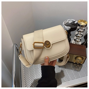 Detailed shot of cream leather bag featuring retro round metal buckle and wide strap