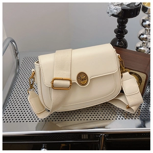 Close-up of retro cream leather crossbody bag with vintage gold portrait emblem detail