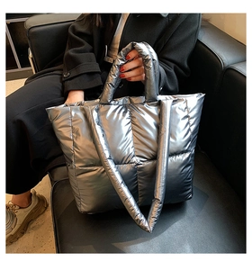 Detail view of large quilted silver puffer tote bag with metallic finish and shoulder straps
