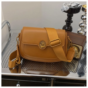Detail of caramel leather crossbody bag with vintage golden medallion and wide strap