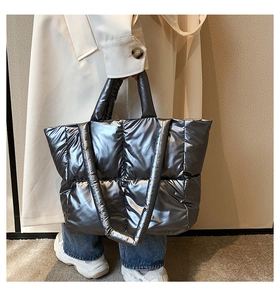 Detailed view of silver quilted down tote bag with metallic finish and padded handles
