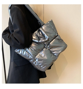 Detail of silver quilted tote bag featuring metallic finish and puffer texture on a model