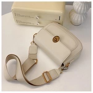 Close-up of cream vintage crossbody bag with golden floral buckle and fabric strap