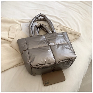 Detail of a bronze quilted puffer tote bag with metallic finish and soft padded handles