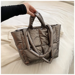 Detail of metallic quilted tote bag showing padded texture and dual carrying straps