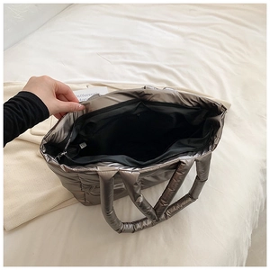 Detailed interior of metallic quilted tote bag with smooth zipper and black lining