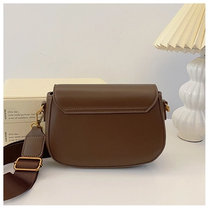 Detail of coffee leather saddle bag with wide fabric strap and gold metal hardware