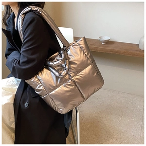 Detail of metallic quilted tote bag with padded shoulder strap and soft down-like texture