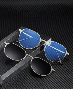 Détail du clip solaire magnétique et de la monture en métal argenté sur fond carbone