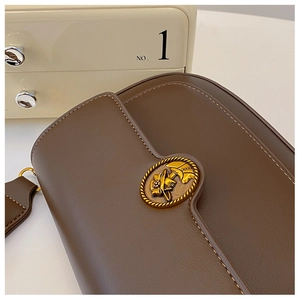 Close-up of vintage brown leather bag featuring an ornate gold embossed metal buckle