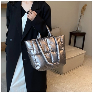 Macro shot of silver quilted puffer tote bag detail with metallic glossy finish