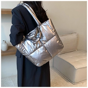Detail of silver metallic quilted tote bag with puffer texture and wide shoulder strap