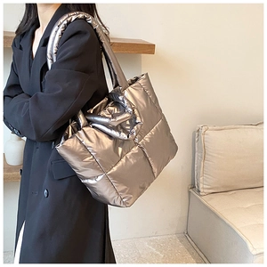 Detail of silver metallic quilted tote bag featuring a high-gloss finish and wide shoulder strap