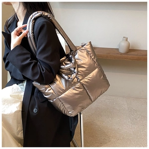 Detail of silver metallic quilted puffer tote bag on shoulder for daily commute