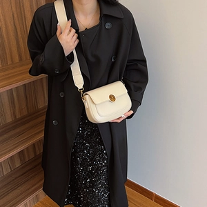 Minimalist beige leather saddle bag with gold buckle and wide canvas shoulder strap
